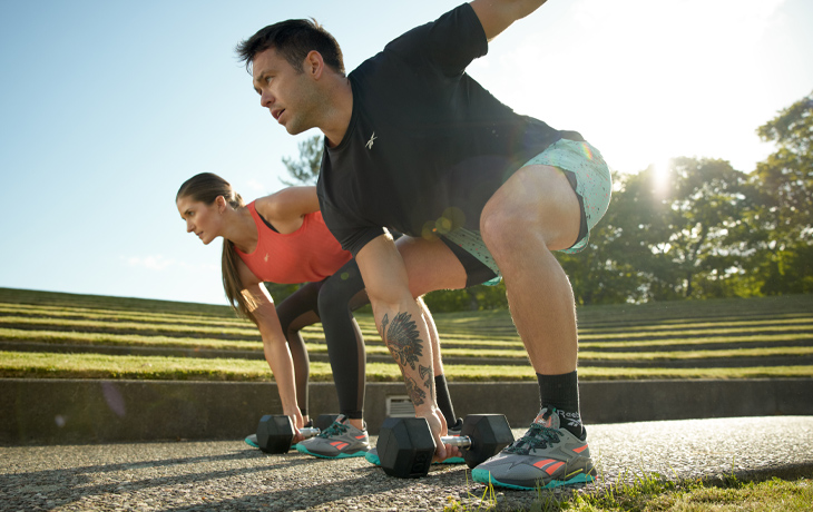 Femme et homme qui s'entraînent à l'extérieur avec des vêtements athlétiques Reebok